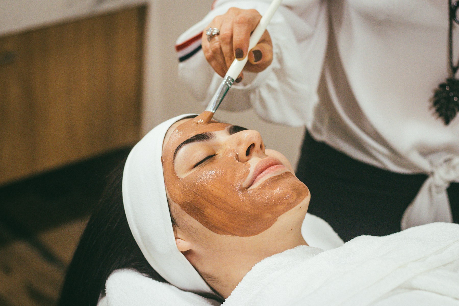 Frau entspannt bei einer Facial-Behandlung mit Gesichtsmaske